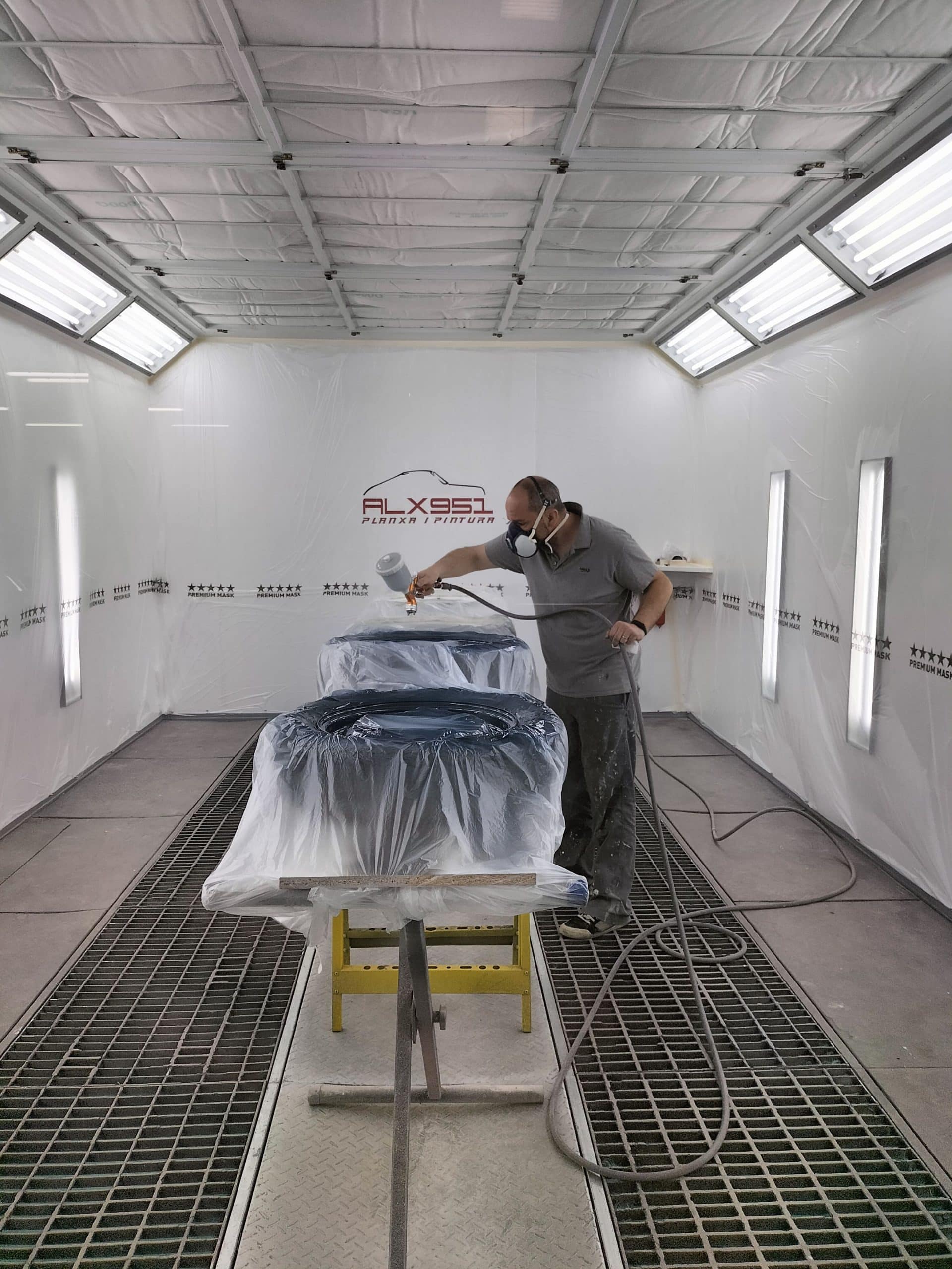 Técnico de ALX951 pintando un vehículo dentro de la cabina propia